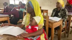 አስናት ጌዲዮን ልጇን ታቅፋ በክፍል ውስጥ