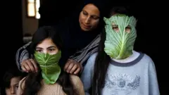أم فلسطينية ترفه عن أطفالها أثناء الطهي بعمل كمامات من ورق الملفوف في مدينة بيت لاهيا في أبريل/نيسان 2020
