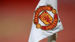 A corner flag at Old Trafford displaying the Manchester United badge