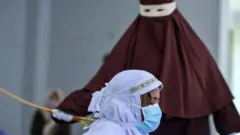 An Indonesian woman is publicly caned as punishment under Aceh province's Sharia laws for being caught with her boyfriend, in March 2021.