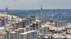 Tepelik alanda yükselen inşaatlar ve daha ileride görüşen bir köprü inşaatı 