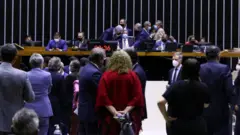 Deputados no plenário, olhando em direção à mesa da Câmara, onde todos estão de máscara contra o coronavírus
