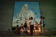 Fiéis católicos lamentam a morte do Papa Francisco com velas em frente a um mural com o retrato do pontífice, em Díli, Timor Leste, em 22 de abril de 2025