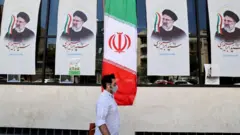 A man walks past an Iranian flag