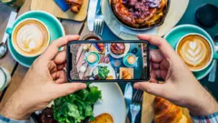 Un homme prend une photo de sa nourriture pour la télécharger sur les réseaux.