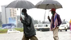 ዣንጥላ የያዙና ጭምብል ያጠለቁ ሰዎች