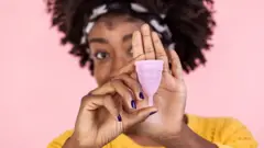 femme noire détenant une coupe menstruelle
