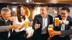 Un grupo de japoneses brinda con cerveza en un restaurante.
