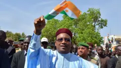 Le président nigérien Mahamadou Issoufou tenant un drapeau nigérien entre les mains