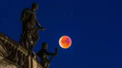 صورة للقمر الدموي المكتمل في عام 2015، وهو يمر فوق مبنى قديم في سماء زرقاء داكنة