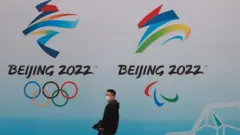 北京水立方一位途人走過2022年北京冬奧會與冬殘奧會標誌（9/4/2021）