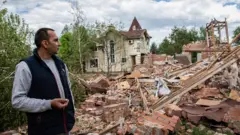 The owner of the building surveys the ruins of his building on the outskirt of the separatist region of Donetsk, 19 May