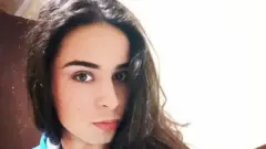 Nikita, 29, is wearing red lipstick and posing for the camera