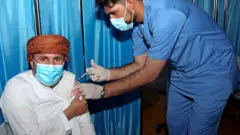 رجل عماني يتلقى جرعة من لقاح فايزر في مجمع السلطان قابوس الرياضي بالعاصمة العمانية