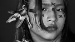 Black and white portrait of a girl with painted designs on her face