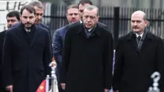 • اردوغان (در مرکز تصویر)، البیرق، وزیر دارایی‌ ( سمت چپ) و سویلو، وزیر کشور در یک مراسم.
