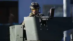 One Ukrainian soja inside armoured vehicle tanda for di west side of di Ukrainian capital of Kyiv on 26 February