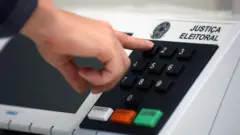 Pessoa digitando números em urna eletrônica