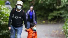 Una familia en Vancouver caminando al aire libre con mascarillas puestas
