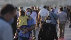 İstanbul'da yüzlerinde maskeyle yürüyen bir aile.