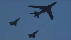 A Xian H-6U in-flight refueling tanker (C) flies in formation with a pair of Chengdu J-10 multirole fighte