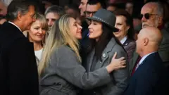 Villarruel e Karina Milei dando um abraço. Há várias pessoas em volta