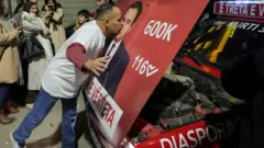 Muškarac ljubi Kurtijev poster zalepljen na haubi automobila