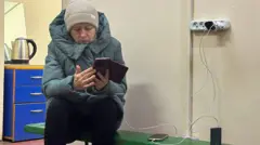 Жінка у синій куртці заряджає гаджети у пункті незламності 