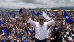 Hernández saluda a sus simpatizantes rodeado de banderas azules del Partido Nacional.
