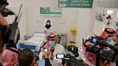 أول سعودي يحصل على تطعيم ضد فيروس كورونا يتحدث إلى الصحفيين من غرفة التطعيم