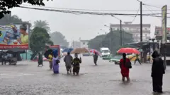 Des personnes marchant dans des eaux de pluie à Abidjan.