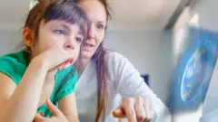 Mãe e filha usando computador