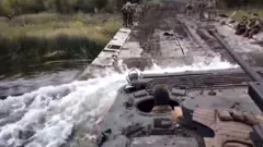 A Ukrainian troop carrier is seen crossing a river in eastern Ukraine