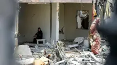Lübnan'ın Toul köyünde yıkılmış evinin enkazında oturan bir kadın