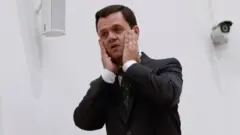 Anderson Torres colocando as duas m'aos no rosto com expressão de desespero