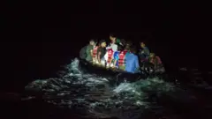 Um bote de borracha cheio de migrantes que cruzam para a ilha grega de Lesvos à noite