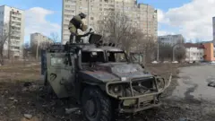An Ukrainian Territorial Defence fighter examines a destroyed Russian infantry mobility vehicle GAZ Tigr after the fight in Kharkiv on February 27, 2022