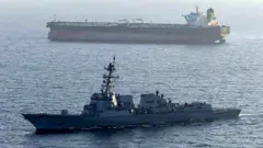 A US military ship is seen in the foreground in the Arabian Sea in April, while another ship is seen in the background.