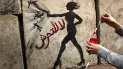 امرأة ترسم على حائط "لا للتحرش"