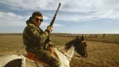 Un grupo de prisioneros en "Angola" custodiados por oficiales armados en los campos de la cárcel de Luisiana en 1990.