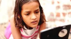 मोबाइल देखती एक बच्ची
