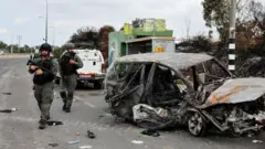 以色列南部阿什克倫（Ashkelon）以軍士兵走過一輛被燒焦汽車（10/10/2023）