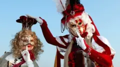 Two masked revellers pose in Venice's Riva degli Schiavoni