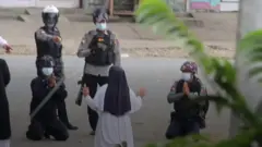 راهبة في ميانمار الرئيسية راكعة أمام الشرطة المسلحة