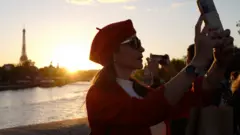 A picture taken on October 8, 2022 in Paris shows people taking pictures at sunset in front of the Eiffel Tower.