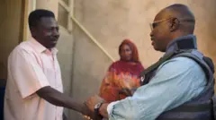 تُظهر الصورة محمد عثمان، مراسل بي بي سي، وهو يصافح أحد جيرانه في مدينته أم درمان التي عاد إليها بعد عامين من الغياب. 