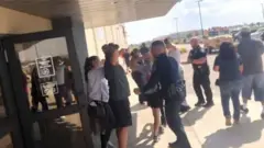 Pessoas sendo revistadas por policiais na porta de cinema