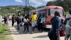 Des visiteurs d'Afrique de l'Ouest - principalement du Cameroun - peu après leur arrivée par vol charter la veille de Noël, essayant de trouver un logement à Antigua, décembre 2022.