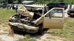 Authorities investigating the truck that is smashed at the front on the side of the road