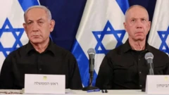 Netanyahu e seu antigo ministro da Defesa, Yoav Gallant, lado a lado; eles são dois homens brancos idosos e há bandeirasjogo que paga bem na blazeIsrael ao fundo 